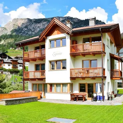 a large building with a green lawn in front of it at Eguia in Selva di Val Gardena