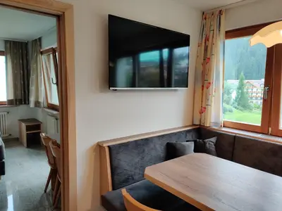 a dining room with a table and a television on the wall at Eguia in Selva di Val Gardena