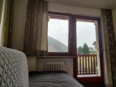 a bedroom with two windows and a bed and a balcony at Eguia in Selva di Val Gardena