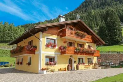 a yellow house with balconies and flowers on it at Appartamenti Cèsa Crepa Neigra in Canazei