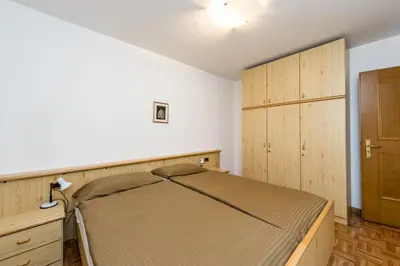 a bedroom with a bed and a wooden cabinet at Appartamenti Cèsa Crepa Neigra in Canazei