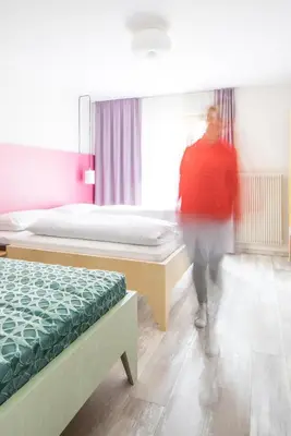 a person walking through a bedroom with two beds at Residence Vis à Vis in Rasùn di Sotto