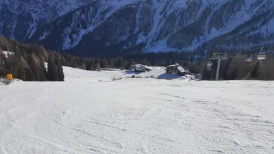 a snow covered slope with a ski lift in the distance at Casa AQ28 sulle piste da sci in Falcade