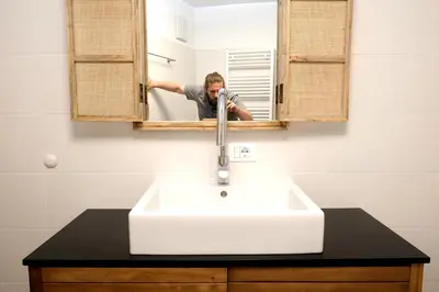 a man is looking in a mirror over a sink at Apartment Plantitsch - Alpstay in Naturno