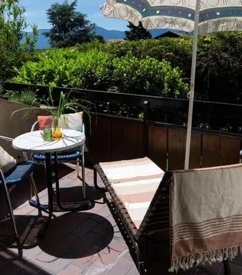 a patio with a table and chairs and an umbrella at Residence Greymold in Rifiano