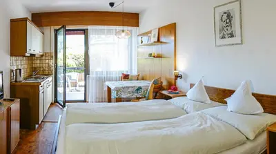 two beds in a room with a kitchen at Residence Greymold in Rifiano