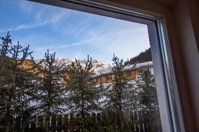 a window with a view of a snow covered mountain at The Muse Apartments in Selva di Val Gardena