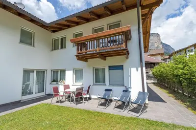 a patio with chairs and a table and a balcony at The Muse Apartments in Selva di Val Gardena