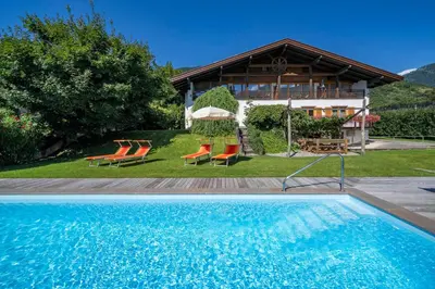 a swimming pool with two chairs and a house at Köstenholzerhof in Lana