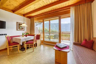 a living room with a table and chairs and a balcony at Köstenholzerhof in Lana