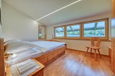 a bedroom with a large bed and a chair at Köstenholzerhof in Lana