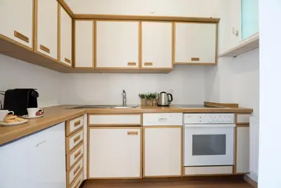a kitchen with white cabinets and a sink at Fior Apartments Pienzenau in Merano