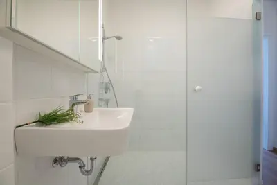 a white bathroom with a sink and a shower at Fior Apartments Pienzenau in Merano