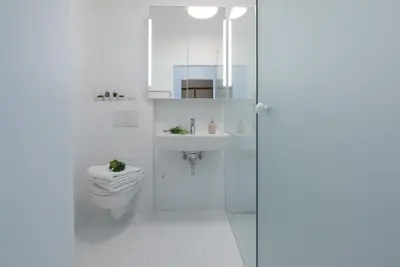 a white bathroom with a toilet and a sink at Fior Apartments Pienzenau in Merano