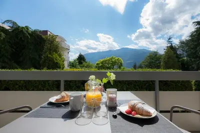 a table with two plates of food and a jar of orange juice at Fior Apartments Pienzenau in Merano