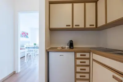 a kitchen with wooden cabinets and a white dishwasher at Fior Apartments Pienzenau in Merano