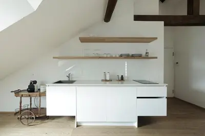 a white kitchen with white counters and a table at Design Apartment in the heart of Bolzano in Bolzano