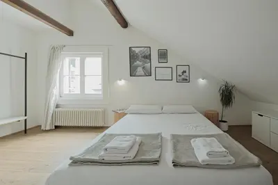 a white bedroom with a large bed with towels on it at Design Apartment in the heart of Bolzano in Bolzano