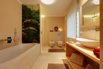 a bathroom with a tub and a sink and two toilets at Crioli Dolomiti Lodge in Villabassa