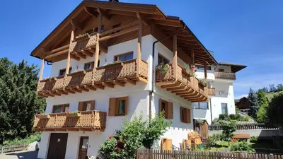 a white building with wooden balconies on it at Ciasa Rosada in San Vigilio Di Marebbe