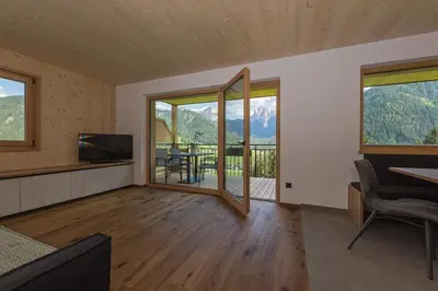 a living room with a television and a table with chairs at Residence Bergheim in Braies