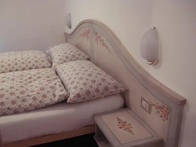 a bed with two pillows sitting next to a wall at Appartamenti Cesa Maria Mountain Hospitality in Canazei