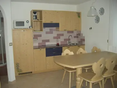 a kitchen with a table and chairs and a sink at Appartamenti Cesa Maria Mountain Hospitality in Canazei