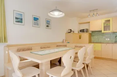a kitchen with a wooden table and chairs at Appartamenti Cesa Maria Mountain Hospitality in Canazei