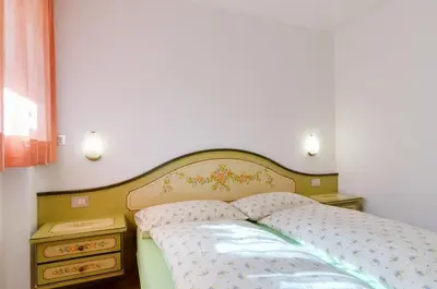 a bedroom with a bed and two night stands at Appartamenti Cesa Maria Mountain Hospitality in Canazei