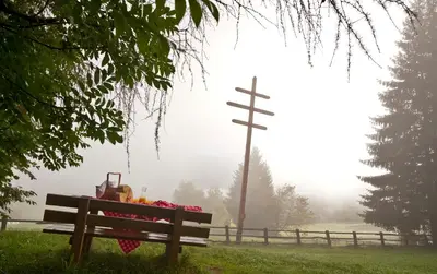 a bench in a field with a cross in the background at Appartementhaus Lechnerhof in Brunico