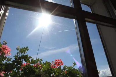 a window with the sun shining in the sky at Appartementhaus Lechnerhof in Brunico