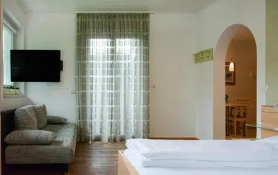 a bedroom with a bed and a chair and a window at Villa Gottfried Appartment in Eggen