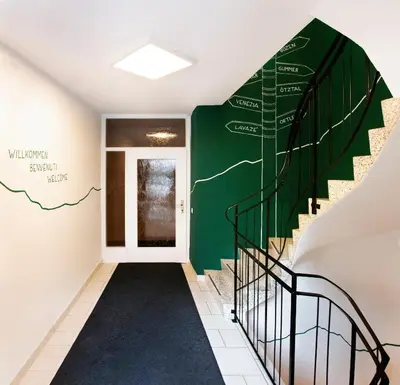 a hallway with stairs and a green wall with a stairwell sign at Villa Gottfried Appartment in Eggen