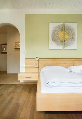 a bedroom with a wooden bed with two paintings on the wall at Villa Gottfried Appartment in Eggen