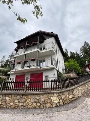 a white building with red doors and a fence at Casa Martina in Malosco