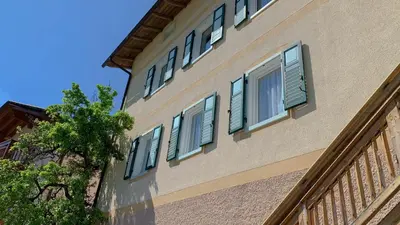 a building with blue shuttered windows on it at Appartamenti LITEGOSA casa vacanza 1 in Panchia