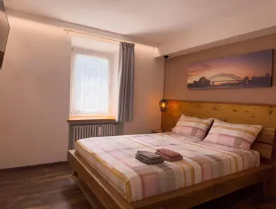 a bedroom with a bed with a striped blanket and a window at Appartamenti LITEGOSA casa vacanza 1 in Panchia