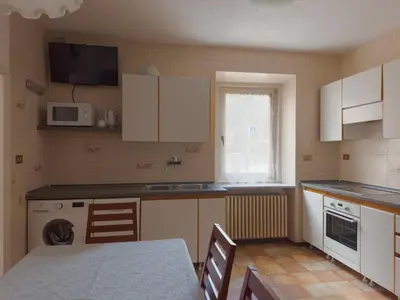 a kitchen with white cabinets and a table and a microwave at Appartamenti LITEGOSA casa vacanza 1 in Panchia
