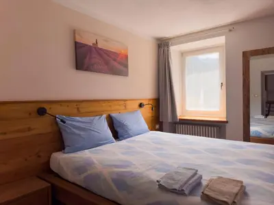 a bedroom with a bed with two towels on it at Appartamenti LITEGOSA casa vacanza 1 in Panchia