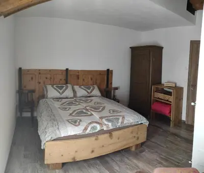 a bedroom with a bed with a wooden headboard at CASA RAINA in Castelfondo
