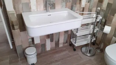a bathroom with a white sink and two baskets at CASA RAINA in Castelfondo