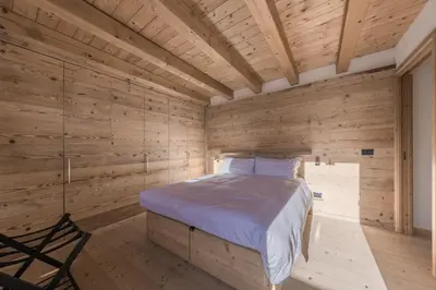 a bedroom with wooden walls and a bed in a room at NeveSole Chalet - Charming Flat Near Dolomiti Ski Slopes in San Vito di Cadore