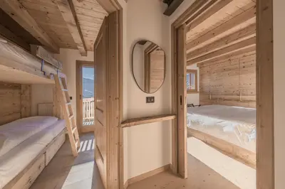 a bedroom with two bunk beds and a mirror at NeveSole Chalet - Charming Flat Near Dolomiti Ski Slopes in San Vito di Cadore