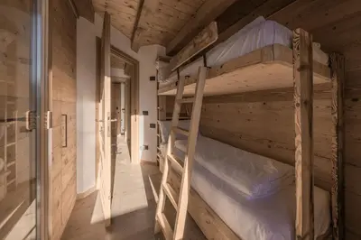 two bunk beds in a room with wooden walls at NeveSole Chalet - Charming Flat Near Dolomiti Ski Slopes in San Vito di Cadore