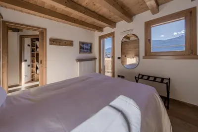 a bedroom with a large bed and a window at NeveSole Chalet - Charming Flat Near Dolomiti Ski Slopes in San Vito di Cadore