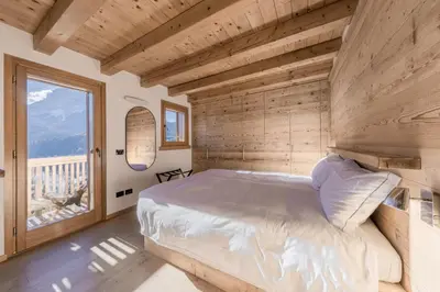 a bedroom with a large bed and a large window at NeveSole Chalet - Charming Flat Near Dolomiti Ski Slopes in San Vito di Cadore