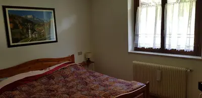 a bedroom with a bed and a picture on the wall at Appartamento con giardino in Predazzo