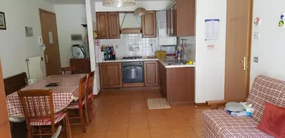 a kitchen with a table and a kitchen with a table and chairs at Appartamento con giardino in Predazzo