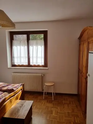 a bedroom with a bed and a table and a window at Appartamento con giardino in Predazzo