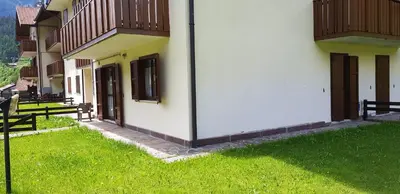 a building with a grassy yard with benches next to it at Appartamento con giardino in Predazzo